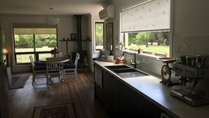 Una cocina moderna con un ventanal grande, una zona de comedor con una mesa y sillas, y una estufa empotrada.