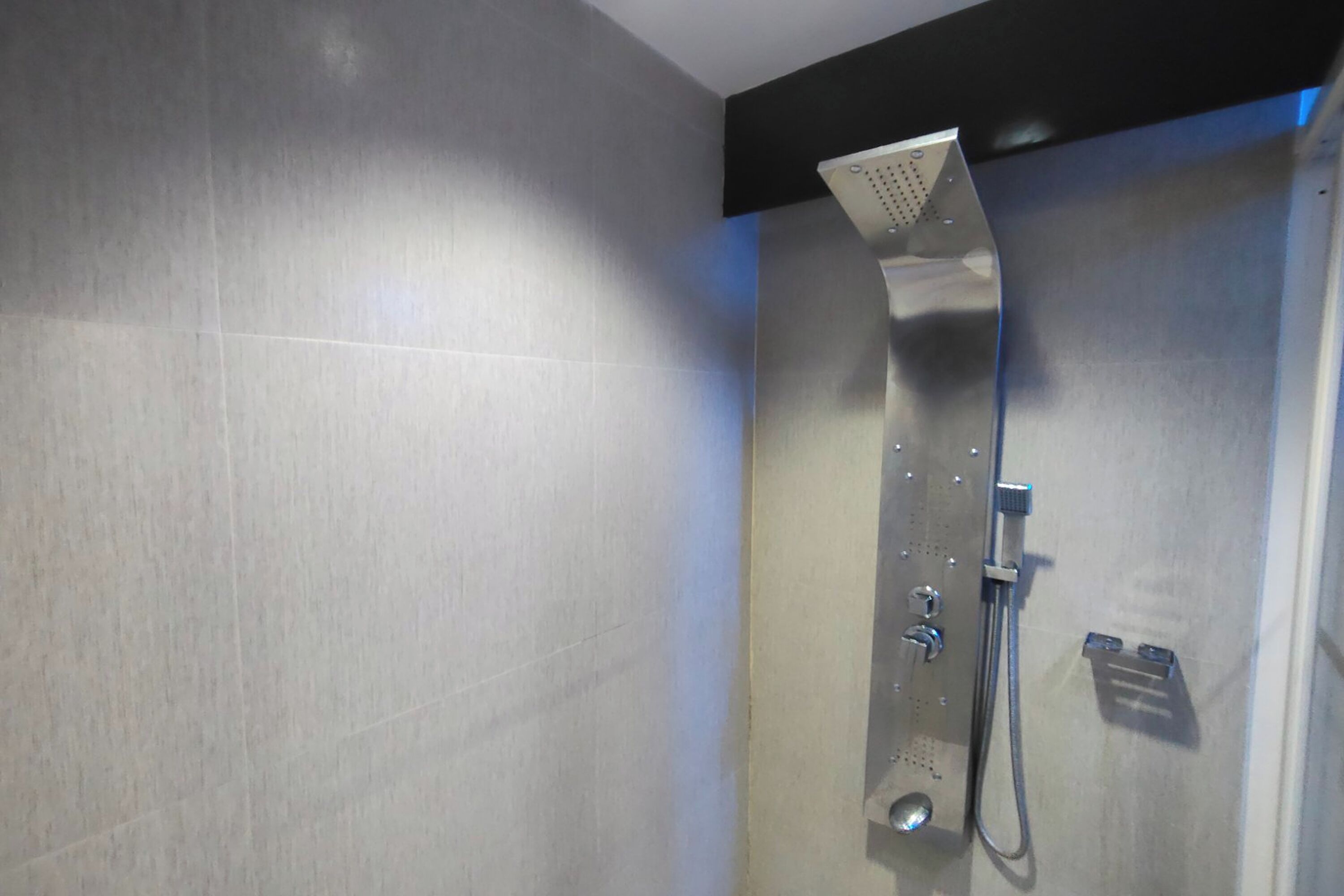 A modern shower with a handheld showerhead and a handheld faucet.