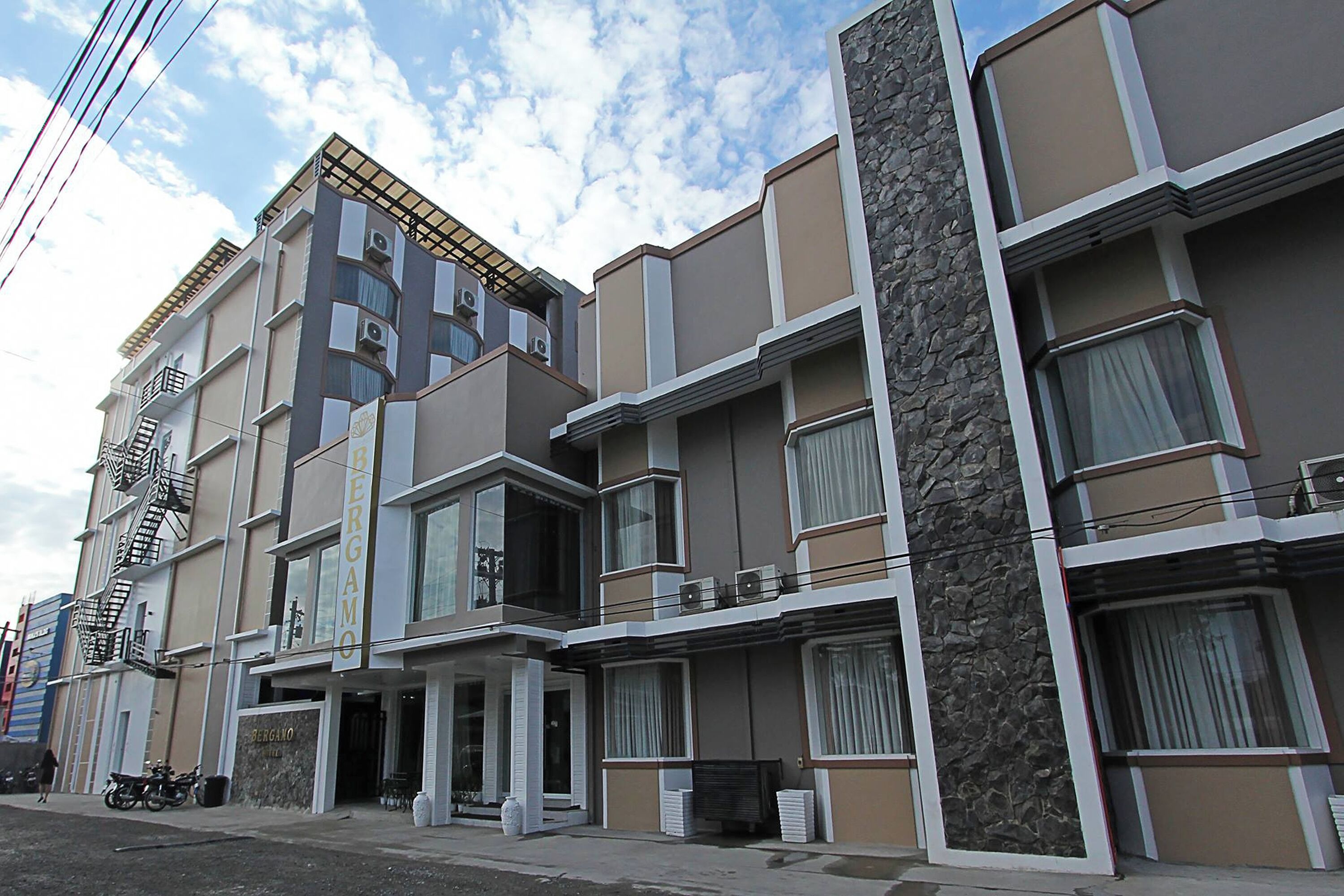 A multi-story residential building with balconies, air conditioning units, and a stone facade.