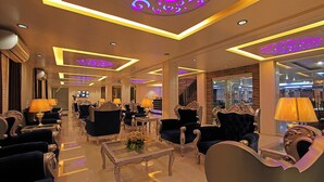 Un lobby de hotel lujoso con muebles ornamentales, una mesa de centro y una iluminación decorativa en el techo.