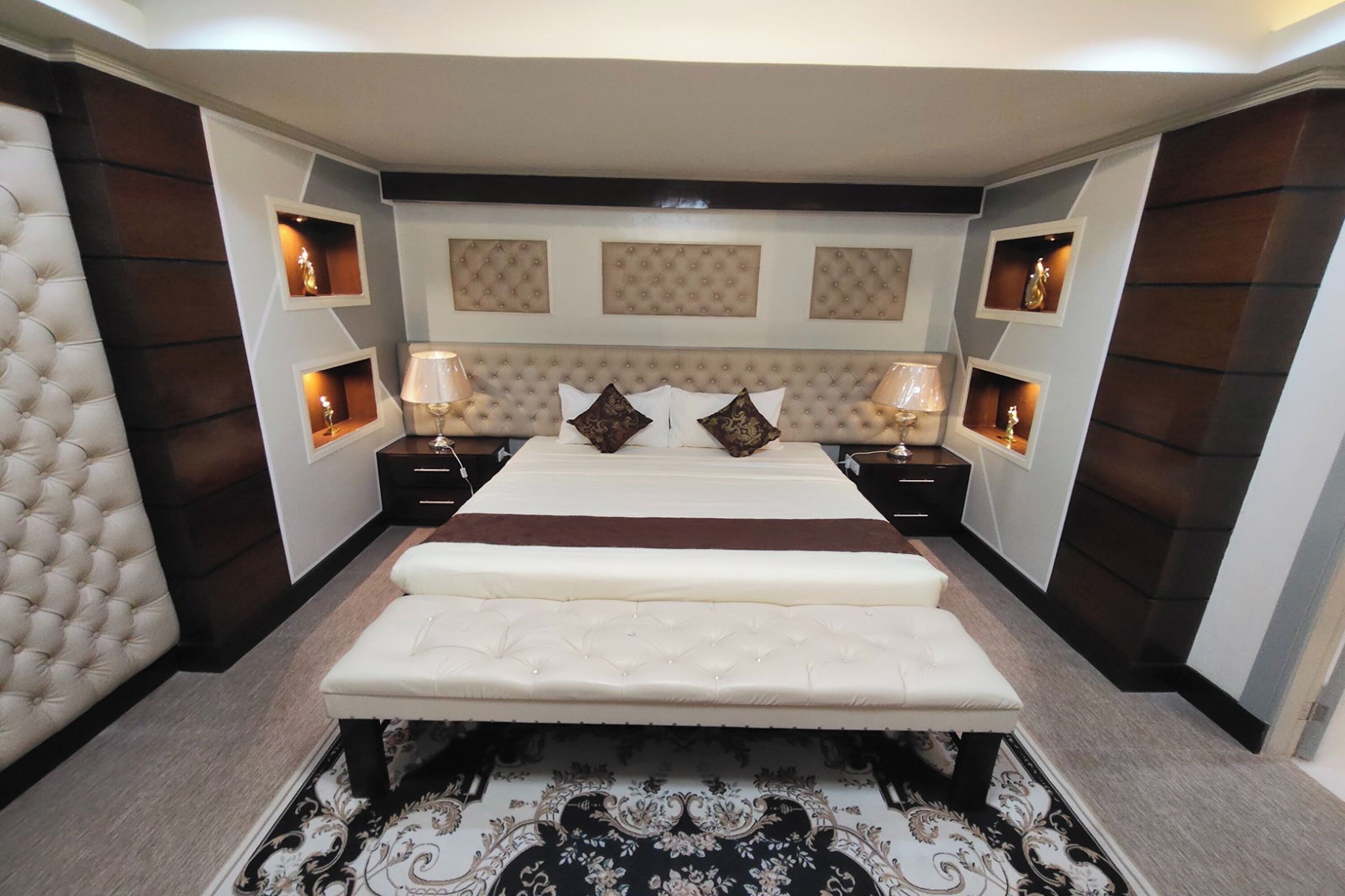 A bedroom with a large bed, two bedside tables, and a decorative rug.