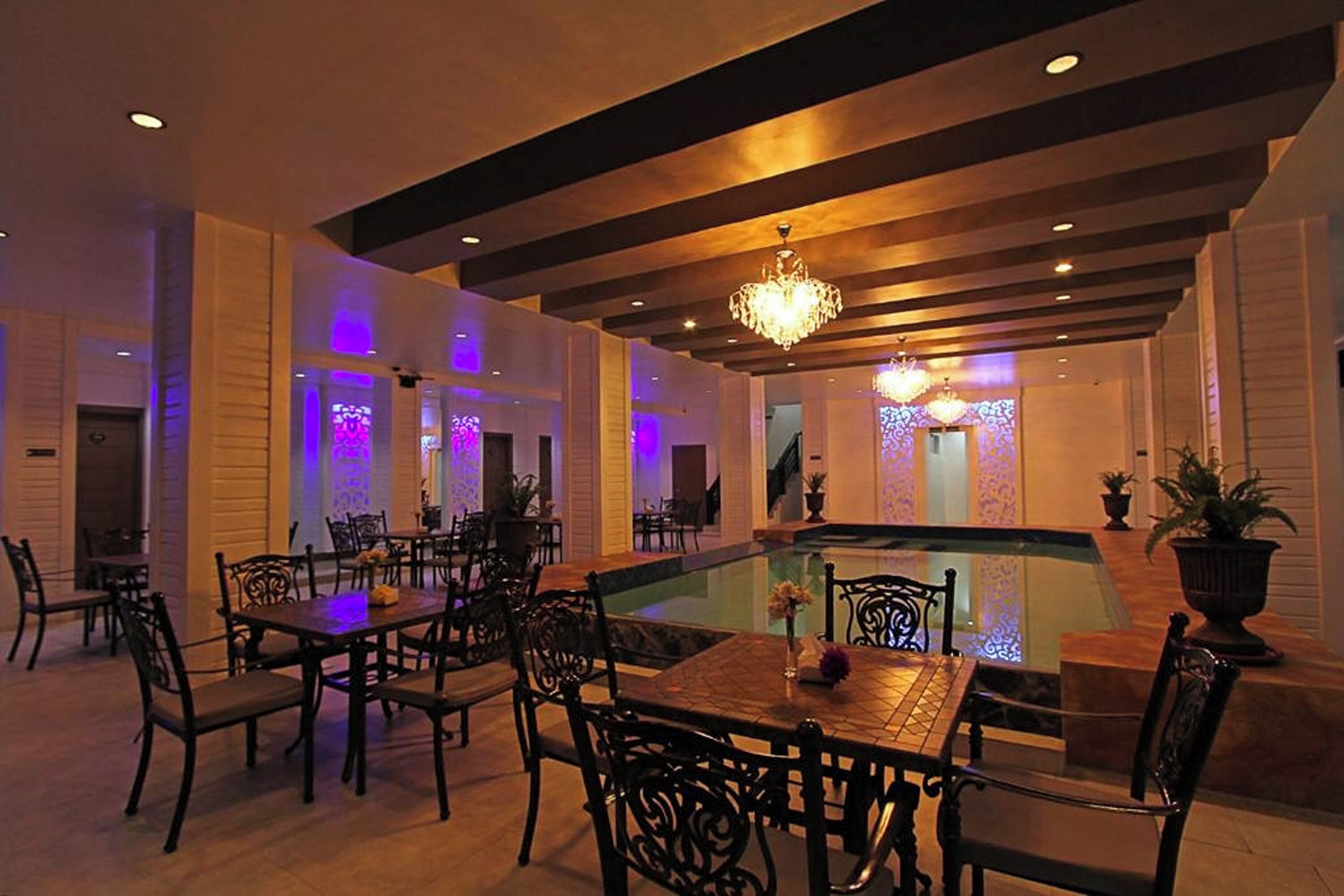 A dining area with tables and chairs, a pool, and a chandelier.