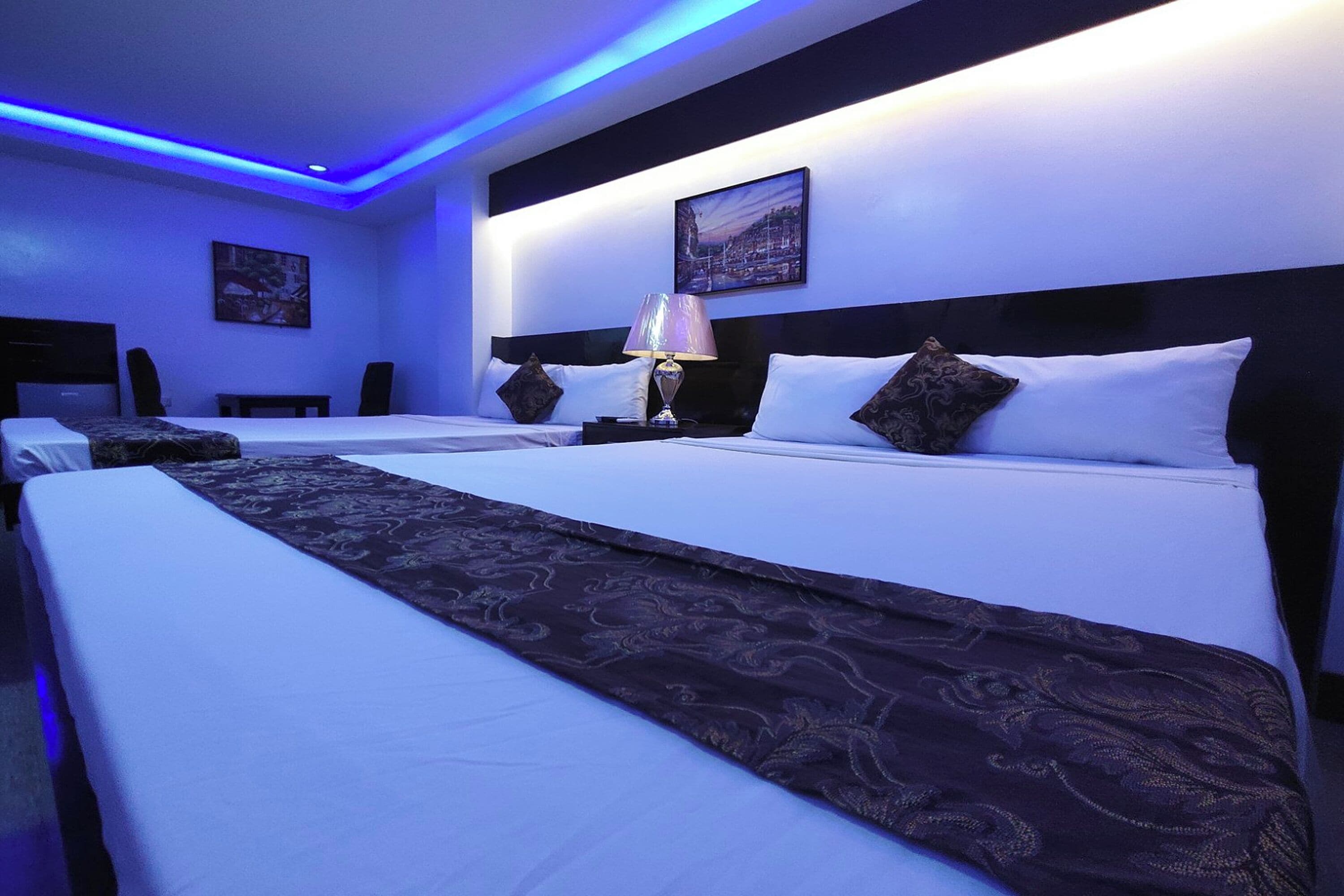 Una habitació d'hotel amb dos llits, una tauleta de nit amb una làmpada i un quadre a la paret.