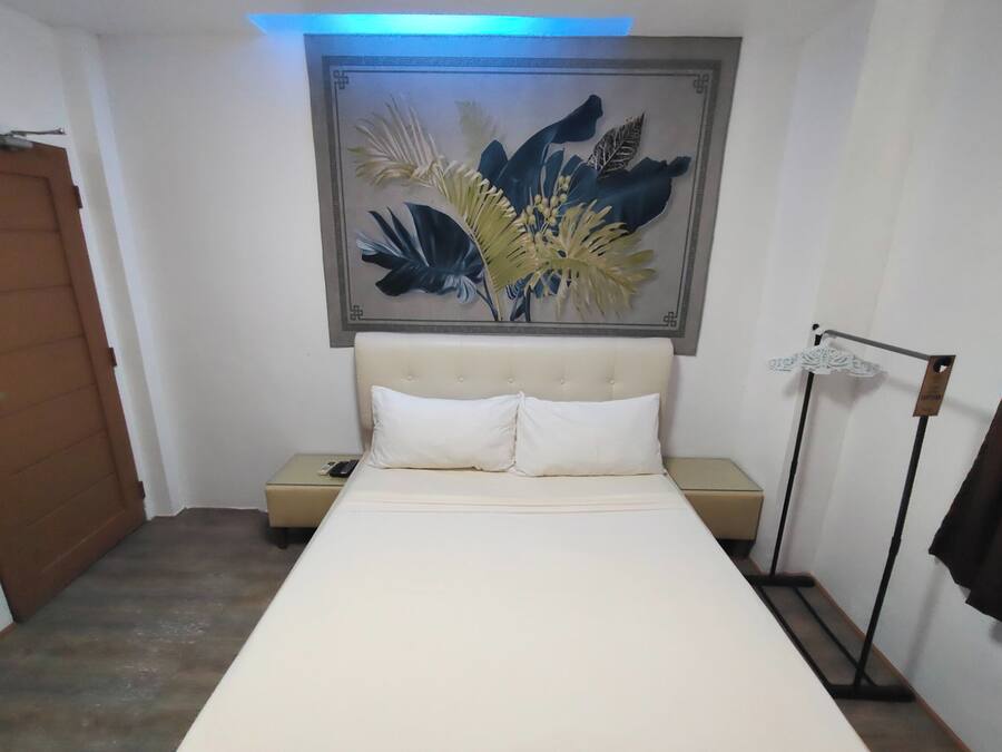 Un dormitorio con cama, mesita de noche, una obra de arte colgada en la pared, armario y lámpara de pie.