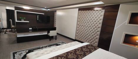 Una habitación de hotel moderna con una cama grande, un escritorio con silla, un televisor y un panel decorativo en la pared.