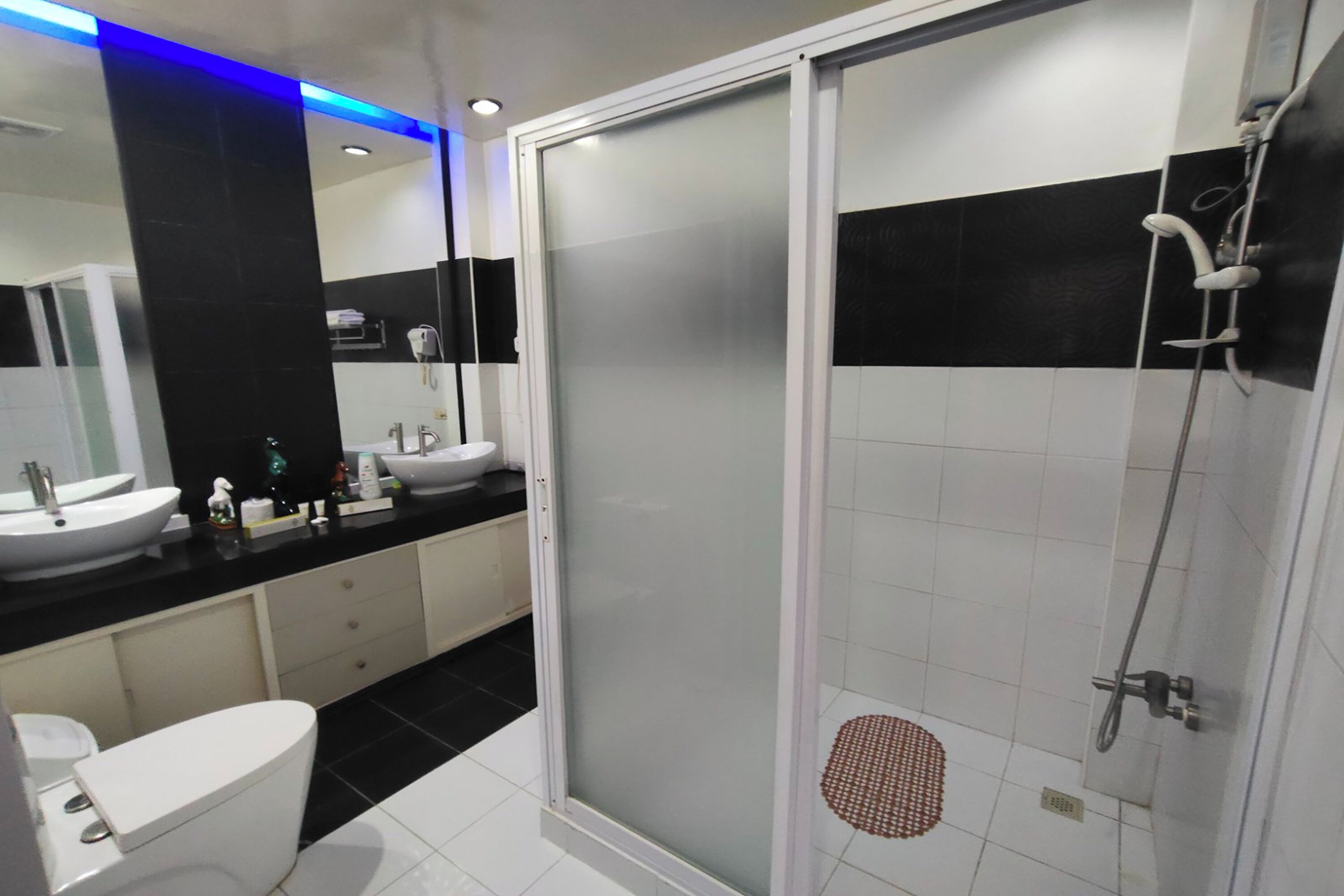 A modern bathroom with a glass-enclosed shower, a white sink, and a black-tiled vanity.