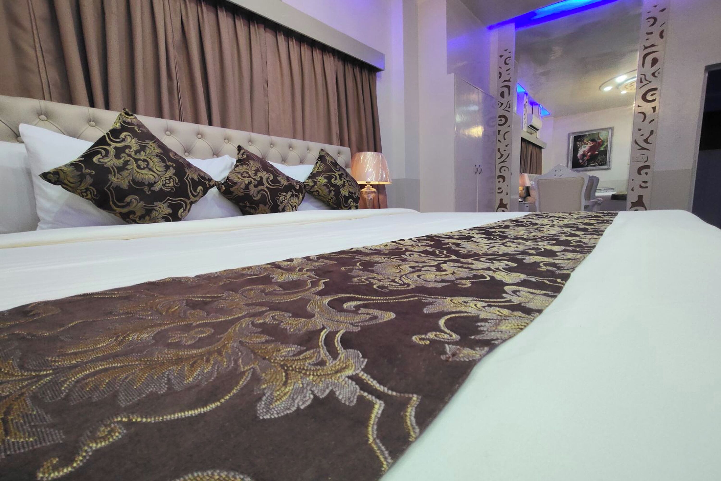 Una camera d'albergo con un letto grande, una testiera trapuntata e una coperta a motivi.