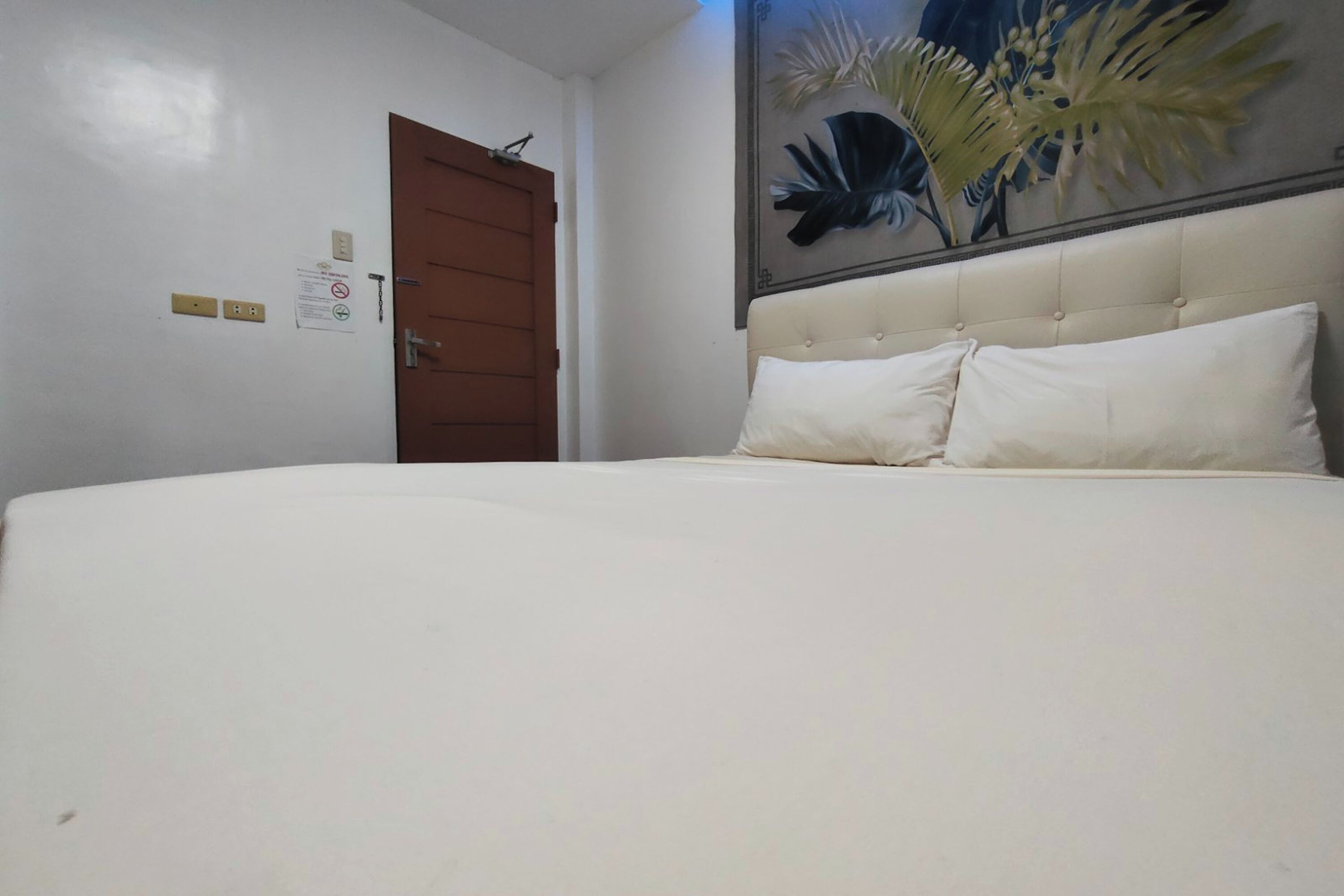 Quarto com uma cama grande, uma porta de madeira e uma obra de arte na parede.
