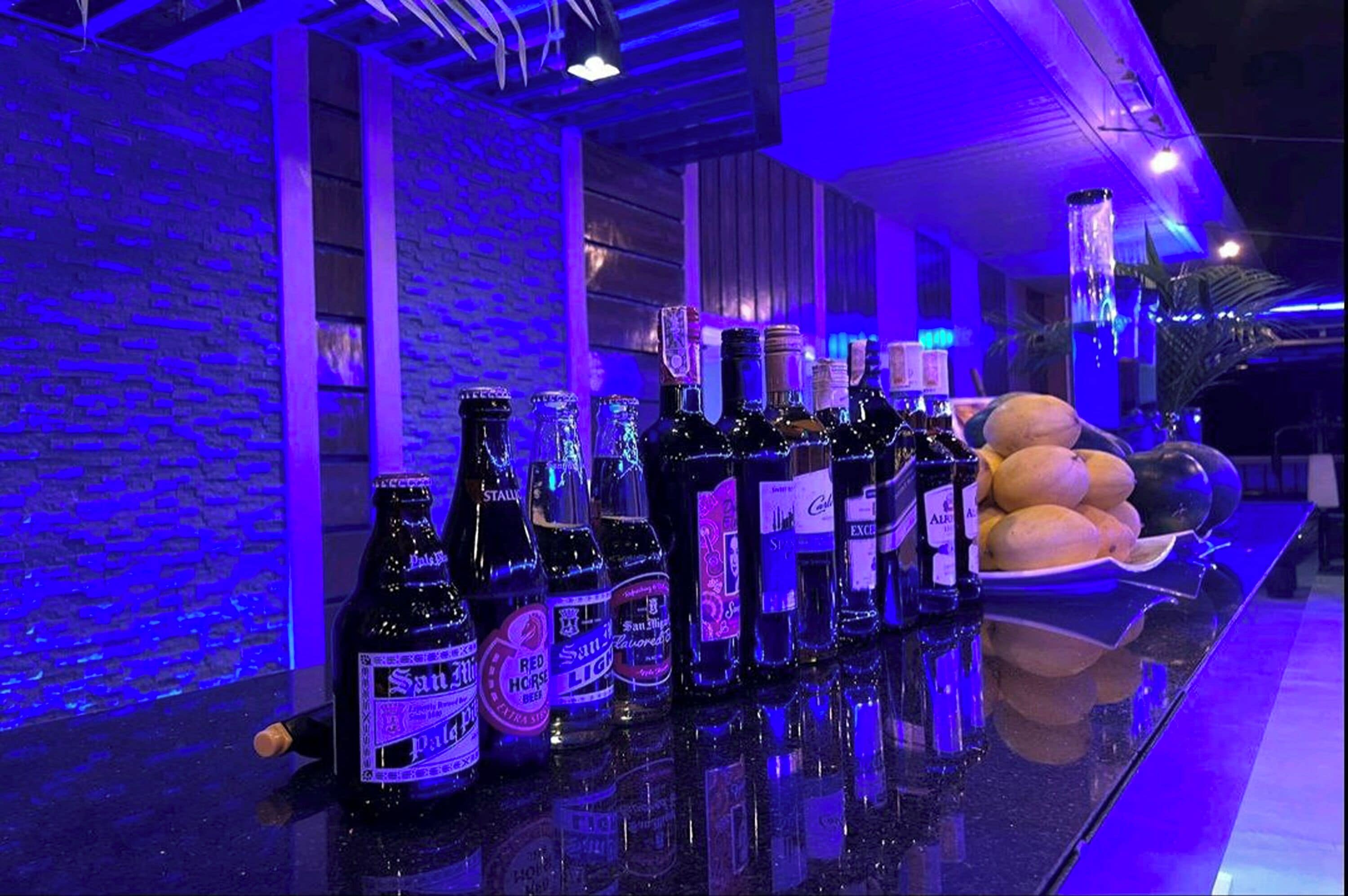 Una zona de bar con una variedad de botellas y un plato de frutas.