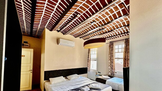 A hotel room with a large bed, a smaller bed, a ceiling fan, an air conditioning unit, and a window with curtains. - Taksim Palace İstanbul Hotel (Istanbul)