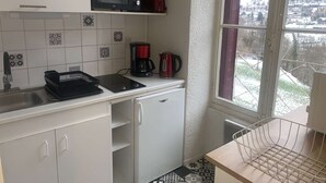 Cocina compacta con microondas, cafetera y un refrigerador pequeño. Una ventana muestra vistas de un paisaje nevado.