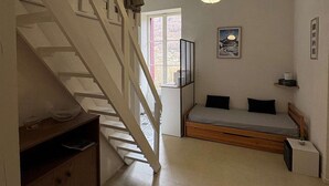 Un dormitorio con cama de madera, una escalera, un colgante de luz y una ventana con vistas.