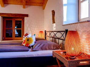 A bedroom with a bed, pillows, a bedside lamp, and a window.