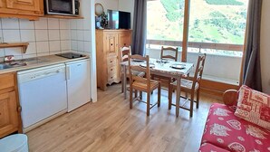 A compact kitchen with a dishwasher, microwave, and a dining area with a table and chairs. - Calm T2 apartment, slopes access, private parking (Les Deux Alpes)