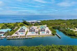 Un gran complejo turístico de varios pisos con múltiples piscinas, un muelle y exuberante vegetación.