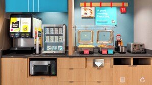 A breakfast bar with a coffee machine, a vending machine, and a toaster. - avid hotels Perry-National Fairground Area by IHG (Perry)