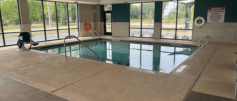 A swimming pool with safety railings, a lifebuoy, and a warning sign.