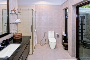 A modern bathroom with a glass shower enclosure, a white toilet, and a vanity with a sink and mirror.