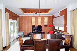 Un salon moderne doté d’un téléviseur à écran plat, de murs recouverts de panneaux en bois et d’un ventilateur de plafond.