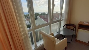 A room with a large window, a round table, two chairs, and a small cabinet. - Sancak Hotel (Istanbul)