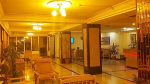 A hotel lobby with a reception desk, seating area, and a large mirror reflecting the space. - Sancak Hotel (Istanbul)