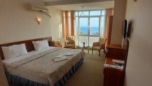 A hotel room with a large bed, a desk, two chairs, a TV, and a view of the sea. - Sancak Hotel (Istanbul)