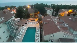 A residential area with a swimming pool surrounded by lounge chairs, a parked truck, and a building with a red roof. - Sancak Hotel (Istanbul)