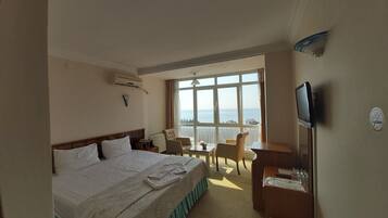 A hotel room with a large bed, a desk, a chair, and a TV.
