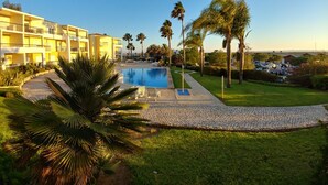 A hotel with a swimming pool, palm trees, and a clear blue sky. - Clube Alvor Ria 103 Luxury sea view 1bed apartment outstanding central location. (Alvor)