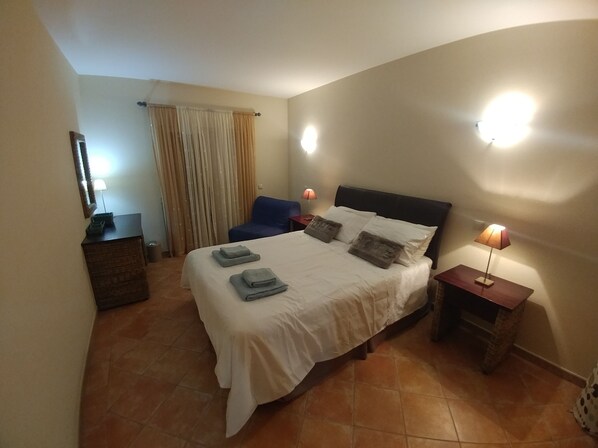 A hotel room with a bed, a desk, a chair, a lamp, and a window with curtains. - Clube Alvor Ria 103 Luxury sea view 1bed apartment outstanding central location. (Alvor)
