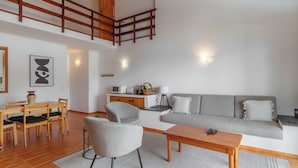 A modern living room with a grey sofa, a wooden coffee table, and a dining area with a wooden table and chairs. - "Casas Azalea - Oceanfront Home with Sunset Views" (Mosteiros)