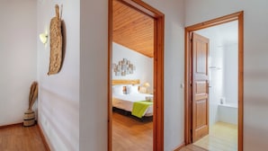 A hallway leading to a bedroom with a wooden ceiling and a bathroom with a bathtub. - "Casas Azalea - Oceanfront Home with Sunset Views" (Mosteiros)