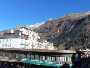 A building with a sign for 'Le Rond Point Brasserie' and a mountain in the background. - Cozy pedestrian studio, pets allowed, balcony - Chamonix (Chamonix-Mont-Blanc)