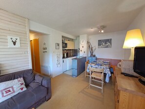 A compact living space with a kitchenette, a dining area, and a seating area with a sofa and a small table.