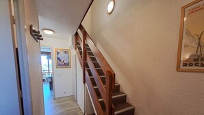 Un escalier avec des marches en bois et une rampe, menant à l’étage supérieur.