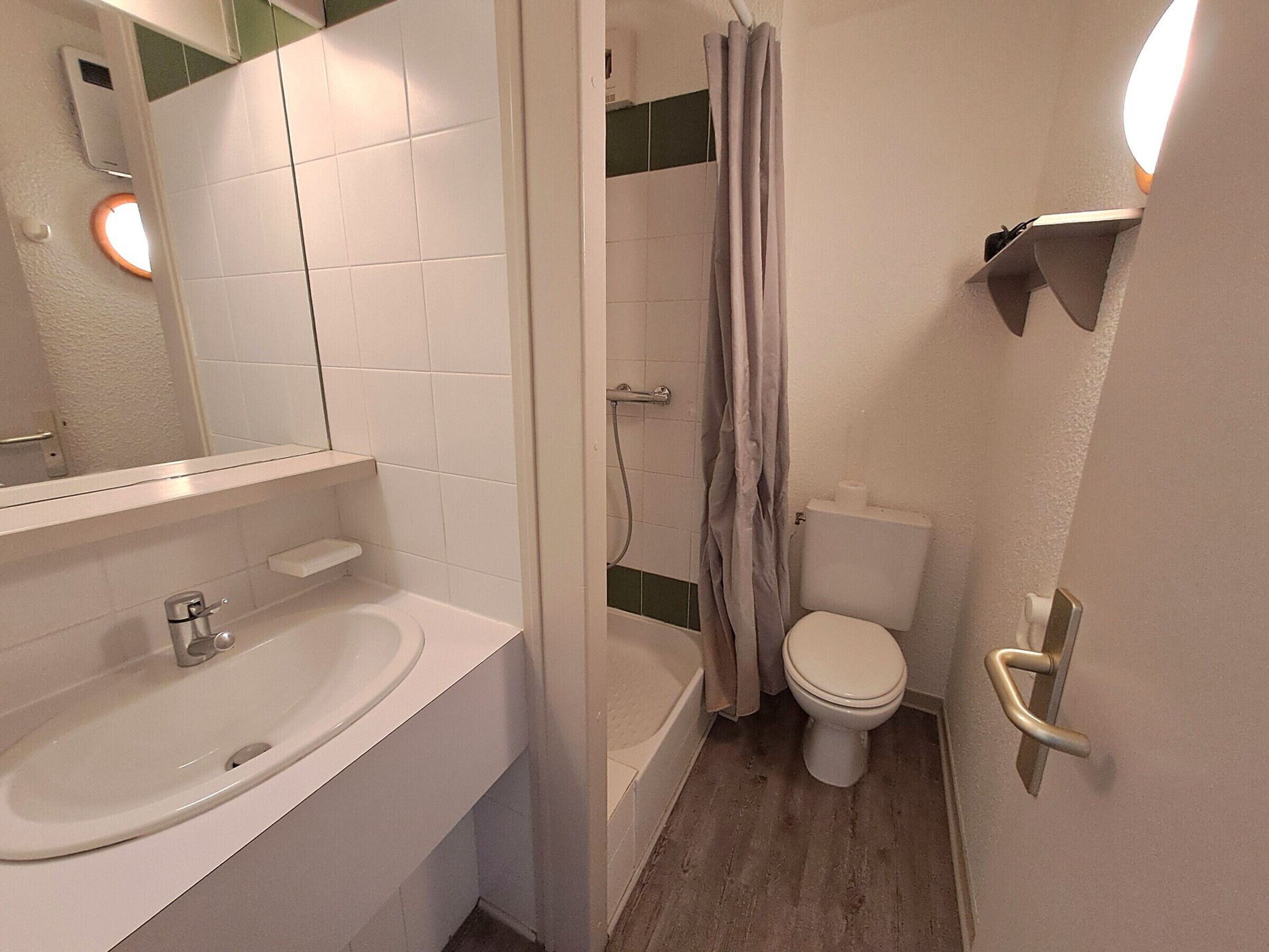 Et badeværelse med badekar, toilet, vask og et spejl.