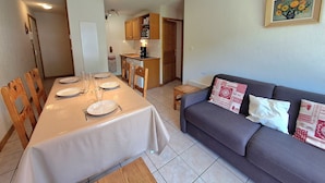 A dining area with a table set for four, a sofa, and a kitchen in the background. - Charming 2-bedroom apartment for 5 people in Les Deux Alpes (Les Deux Alpes)