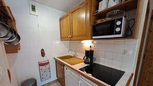 A compact kitchen with wooden cabinets, a microwave, a coffee maker, and a dishwasher. - Charming 2-bedroom apartment for 5 people in Les Deux Alpes (Les Deux Alpes)
