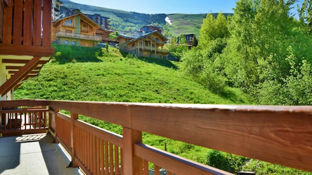 A wooden balcony with a view of traditional houses and a green hillside. - Charming 2-bedroom apartment for 5 people in Les Deux Alpes (Les Deux Alpes)