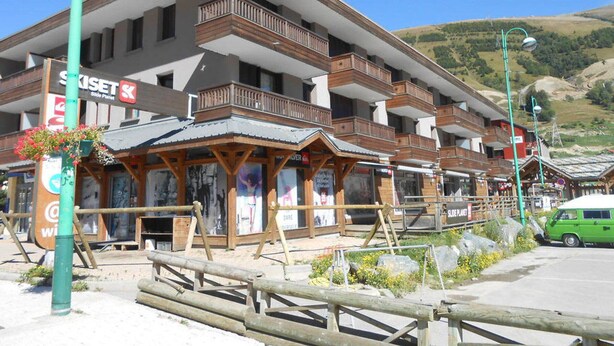 Et hotel med flere etager, altaner og gelændere i træ, samt et skilt med 'SkiSet'.