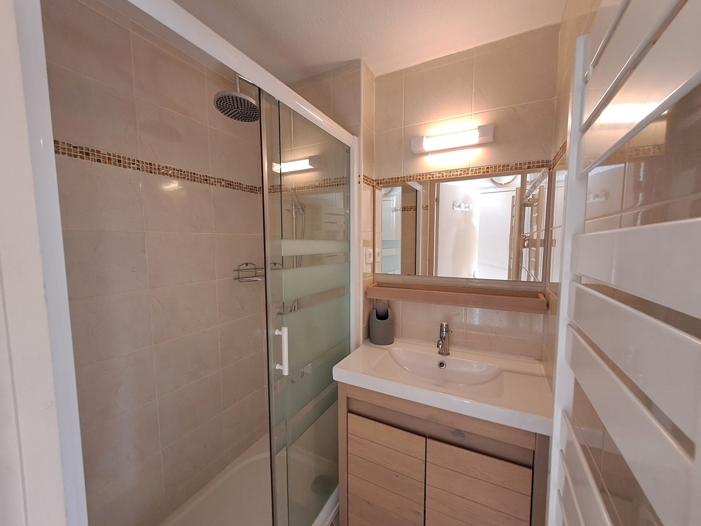 Une salle de bain moderne avec une douche à parois de verre, un meuble-lavabo et un miroir au-dessus du meuble à pharmacie.