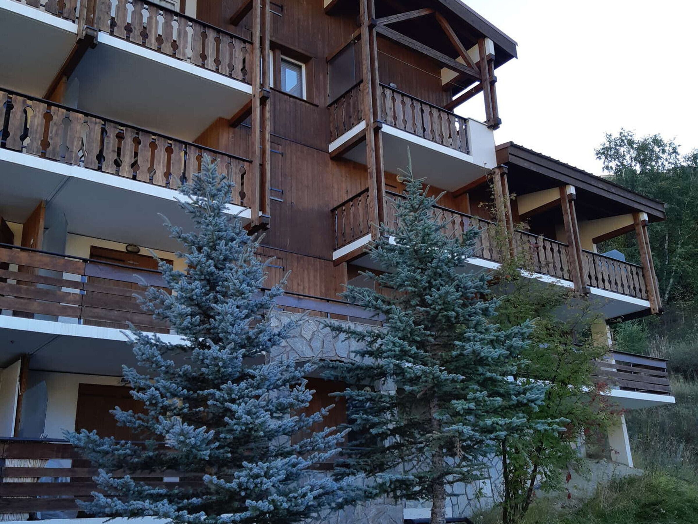 Un immeuble à plusieurs étages, doté de balcons en bois et d’une façade en pierre.