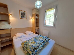 A bedroom with a bed, bedside tables, a wardrobe, a window, and a wall-mounted light fixture. - Spacious 2-Room, Slope View, Pets Allowed (Les Deux Alpes)