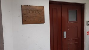 A wooden sign with "TCRINS" on a white wall, a red door with a window, and a doorbell.