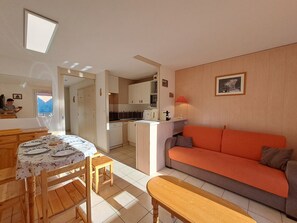 Un espace de vie compact comprenant un coin repas, une kitchenette et un canapé.