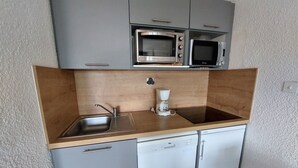 Une petite cuisine équipée comprenant un évier, deux lave-vaisselle, une machine à café et deux micro-ondes encastrés.