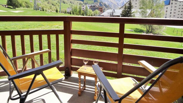 Un balcon donnant sur un champ verdoyant et des montagnes.