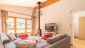 A modern living room with a large sofa, a TV, and a fireplace. - 4-bedroom duplex with pool, spa, and parking at Arcs 1800 (Les Arcs 1800)