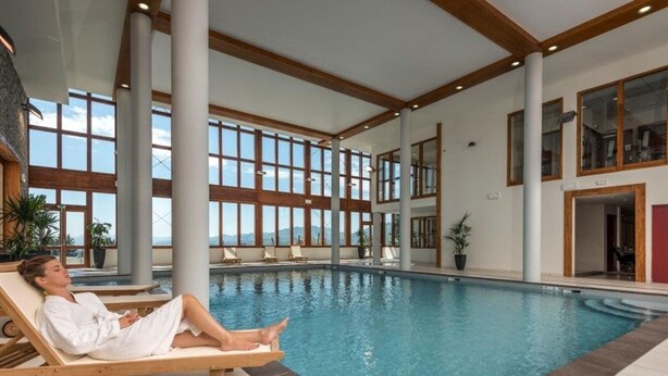 An indoor swimming pool with a person relaxing on a lounge chair. - 4-bedroom duplex with pool, spa, and parking at Arcs 1800 (Les Arcs 1800)