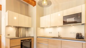 A modern kitchen with wooden cabinets, a stainless steel range hood, a built-in oven, a microwave, and a coffee machine. - 4-bedroom duplex with pool, spa, and parking at Arcs 1800 (Les Arcs 1800)